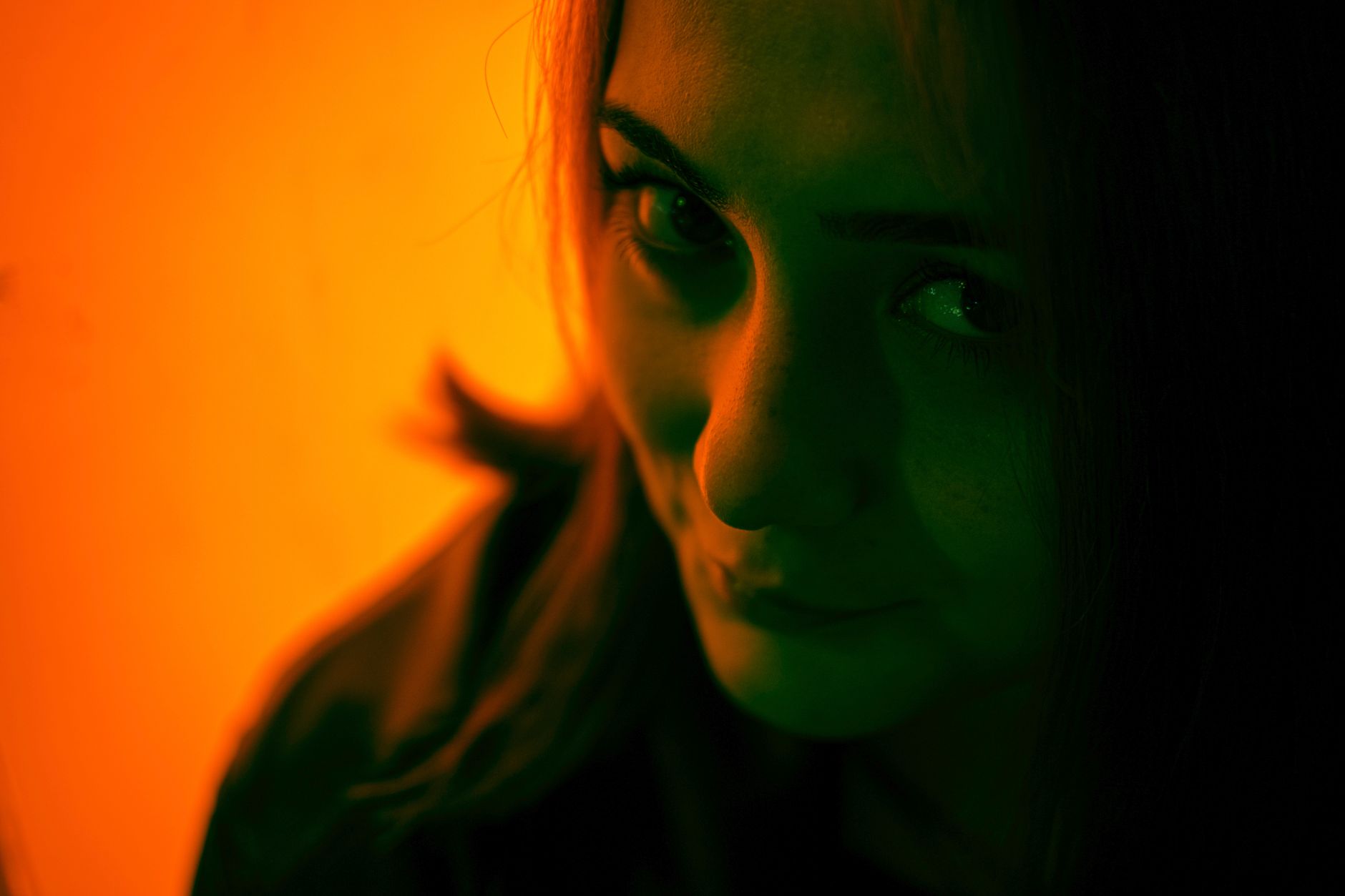 A woman lit by warm orange light at dusk, mid-thought