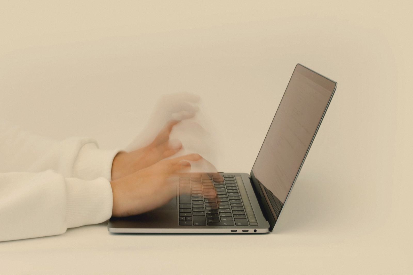 Hands blurred with speed typing on a laptop keyboard