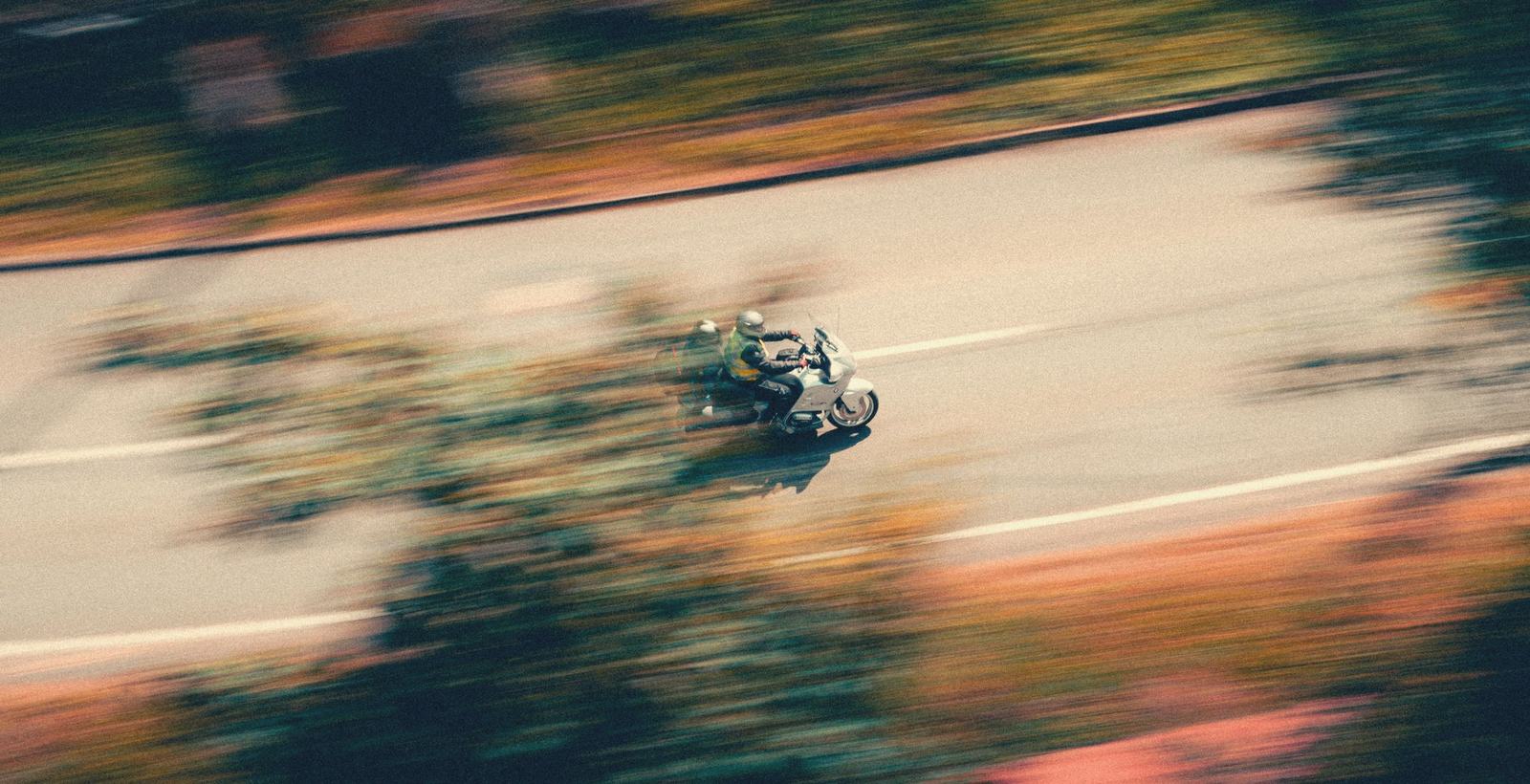Two riders on a motorbike sweeping through an autumn road, the world blurred warm
